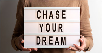 Hands hold a board that says Chase Your Dreams